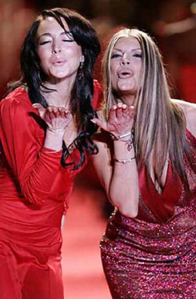 Lindsay Lohan wearing a red wrap dress by Calvin Klein and Fergie from the Black Eyed Peas in a spectacular Daniel Swarovski dress together on the runway for The Heart Truth's Red Dress Collection 2006 Fashion Show at Olympus Fashion Week.