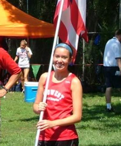 Emly Infeld at a track meet holding a flag