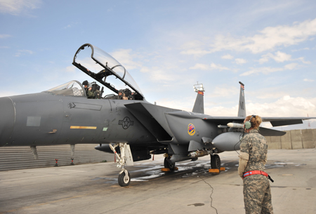 Staff Sgt. Tamara Rhone, 455th Expeditionary Aircraft Maintenance Squadron crew chief, waits for Maj. Christine Mau, 455th Air Expeditionary Wing executive officer and an F-15E Strike Eagle pilot, and Capt. Jennifer Morton, 389th Expeditionary Fighter Squadron weapons system officer, dons their helmet before take-off at Bagram Airfield, Afghanistan, March 29, 2011. Members from the 389th EFS help make this combat mission to be flown, planned, and maintained entirely by females. (U.S. Air Force photo by Senior Airman Sheila deVera)